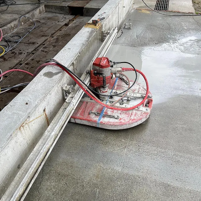 Betongsag med røde slanger plassert på et betonggulv med vann rundt.